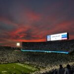 lots of people watching football game during sunset